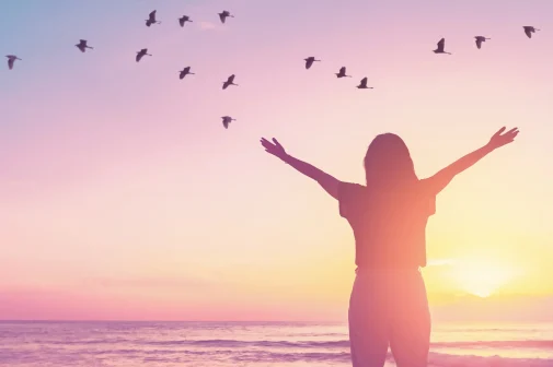 Woman standing by the sea symbolising calm, strength and emotional renewal.